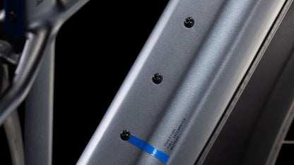 Nahaufnahme des CUBE Reaction Hybrid Pro 800 Allroad metallicgrey'n'black 2025 Metallic-Rahmens mit drei schwarzen Schrauben am Unterrohr, blauem Streifen, kleiner Schrift und hydraulischen Shimano XT-Scheibenbremsen vor schwarzem Hintergrund.