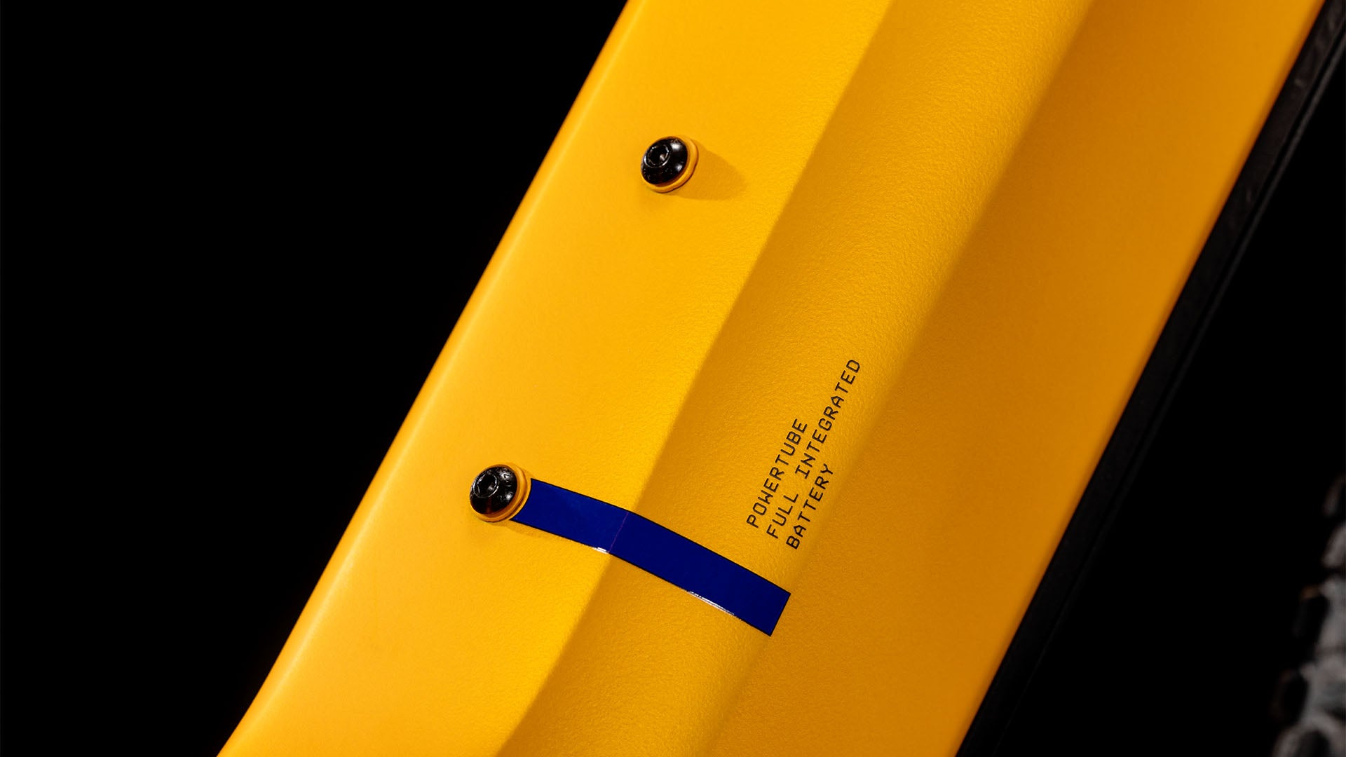 Nahaufnahme eines CUBE Reaction Hybrid SLX 800 spectraorange´n´violet Easy Entry 2025 Rahmens mit zwei Befestigungsschrauben, blauem Akzent und dem Schriftzug „PowerTube Fully Integrated Battery“. Der Fahrradreifen ist rechts teilweise sichtbar.