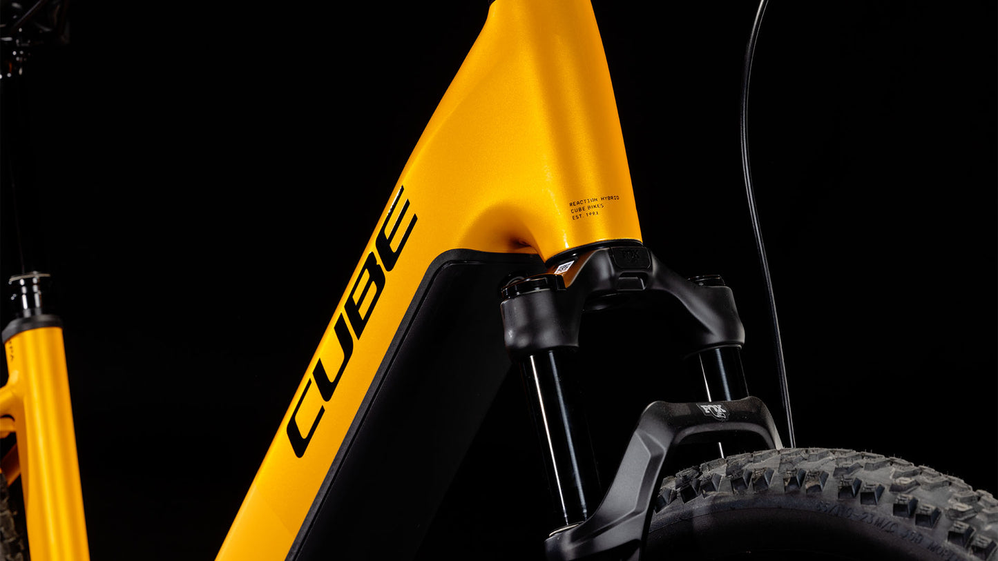 Nahaufnahme eines Cube Reaction Hybrid SLX 800 spectraorange´n´violet Easy Entry 2025-Rahmens mit CUBE-Branding, mit der Vorderradfedergabel und einem Teil des Vorderrads vor einem schwarzen Hintergrund.