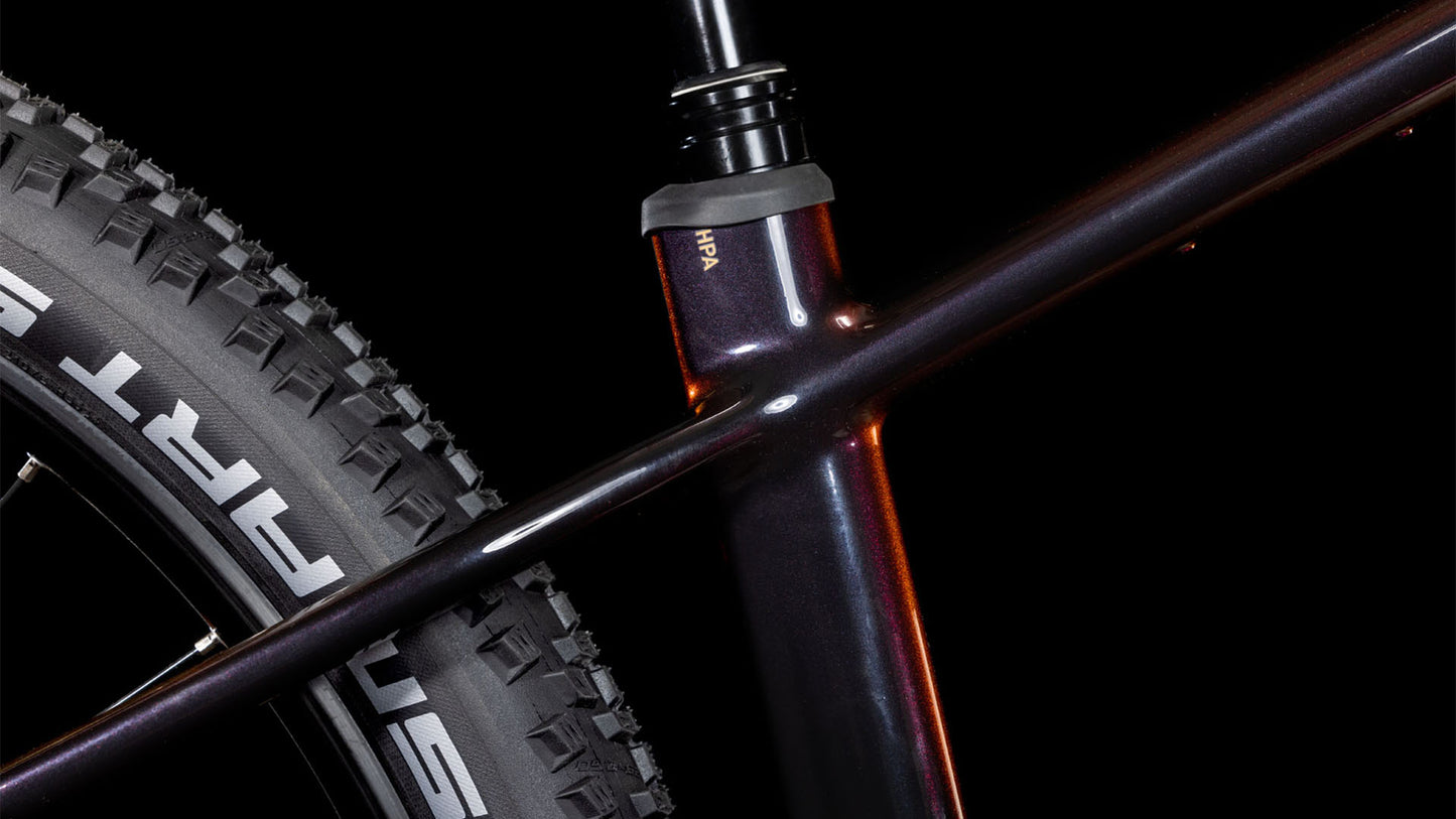 Nahaufnahme des CUBE Reaction Hybrid SLT 800 solareclipse'n'bronze 2025 Rahmens, die das Sitzrohr, das Oberrohr und den Hinterreifen mit SCHWALBE Branding zeigt. Der schwarze Hintergrund unterstreicht das schlanke Design und die fortschrittliche Sram XO Eagle Schaltung.