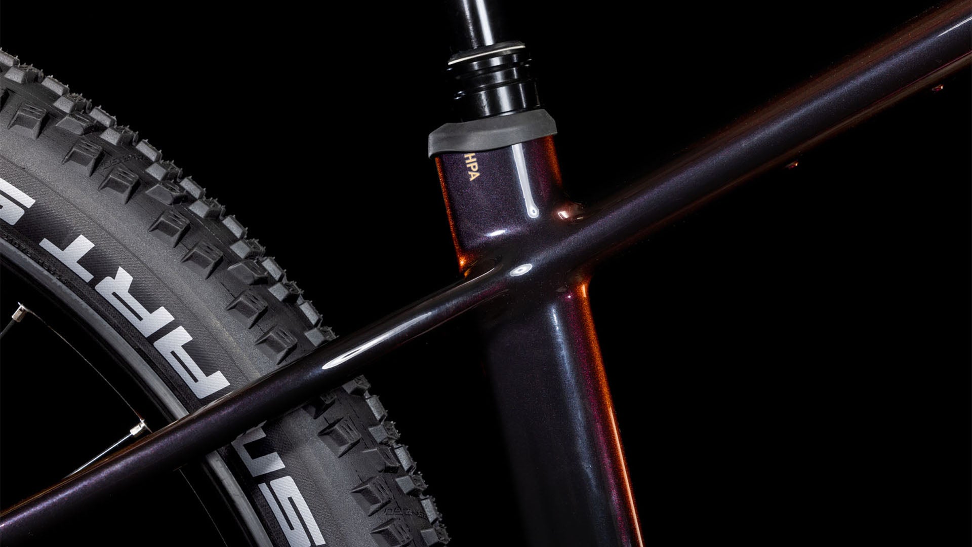 Nahaufnahme des CUBE Reaction Hybrid SLT 800 solareclipse'n'bronze 2025 Rahmens, die das Sitzrohr, das Oberrohr und den Hinterreifen mit SCHWALBE Branding zeigt. Der schwarze Hintergrund unterstreicht das schlanke Design und die fortschrittliche Sram XO Eagle Schaltung.