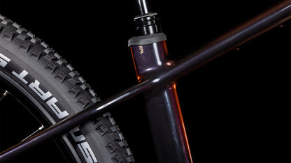 Nahaufnahme des CUBE Reaction Hybrid SLT 800 solareclipse'n'bronze 2025 Rahmens, die das Sitzrohr, das Oberrohr und den Hinterreifen mit SCHWALBE Branding zeigt. Der schwarze Hintergrund unterstreicht das schlanke Design und die fortschrittliche Sram XO Eagle Schaltung.