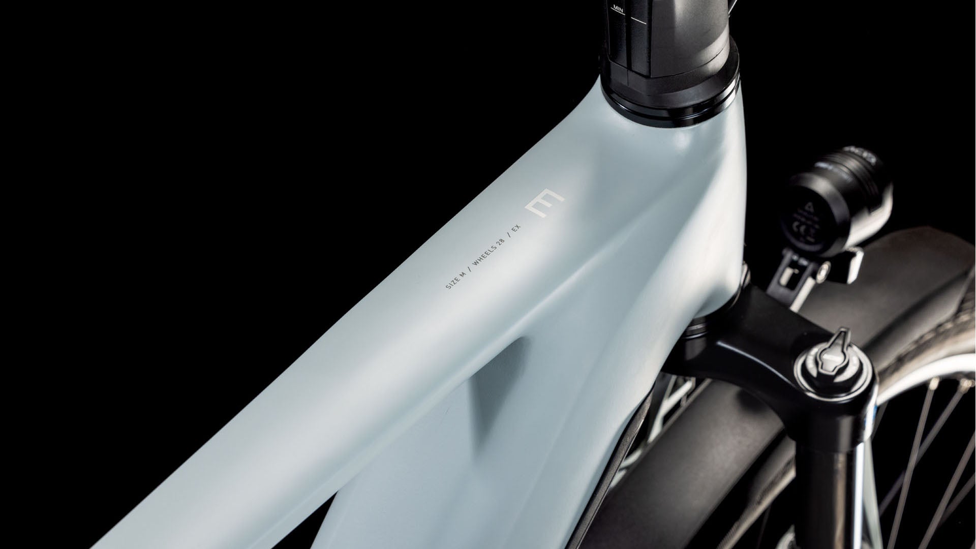 Eine Nahaufnahme des matt hellgrauen Rahmens und der Vordergabel des CUBE Kathmandu Hybrid EX 800 haze´n´black 2025 hebt sein schlankes, minimalistisches Design und den fortschrittlichen Bosch CX-Motor vor einem schwarzen Hintergrund hervor.