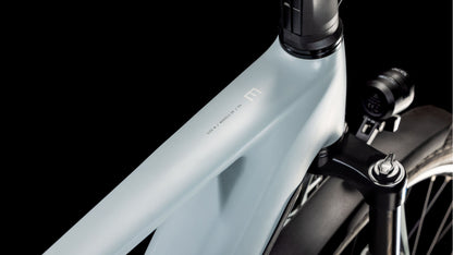 Eine Nahaufnahme des matt hellgrauen Rahmens und der Vordergabel des CUBE Kathmandu Hybrid EX 800 haze´n´black 2025 hebt sein schlankes, minimalistisches Design und den fortschrittlichen Bosch CX-Motor vor einem schwarzen Hintergrund hervor.