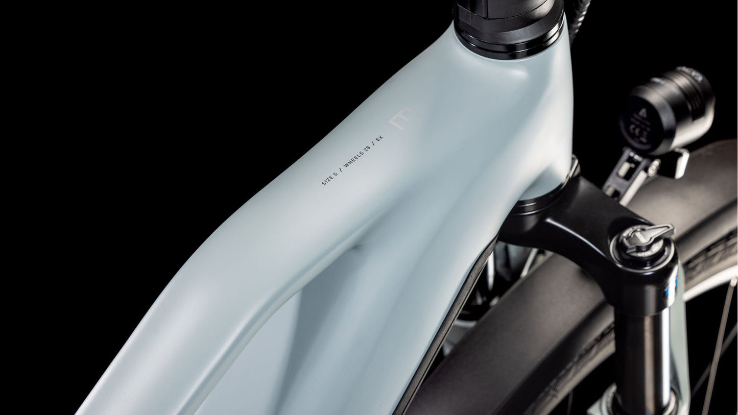 Nahaufnahme des matt-hellgrauen Rahmens und der Federgabel des CUBE Kathmandu Hybrid EX 800 haze´n´black Trapeze 2025 mit minimalistischem Design vor schwarzem Hintergrund. Ausgestattet mit einem Bosch CX Motor für ein entspanntes Fahrgefühl.