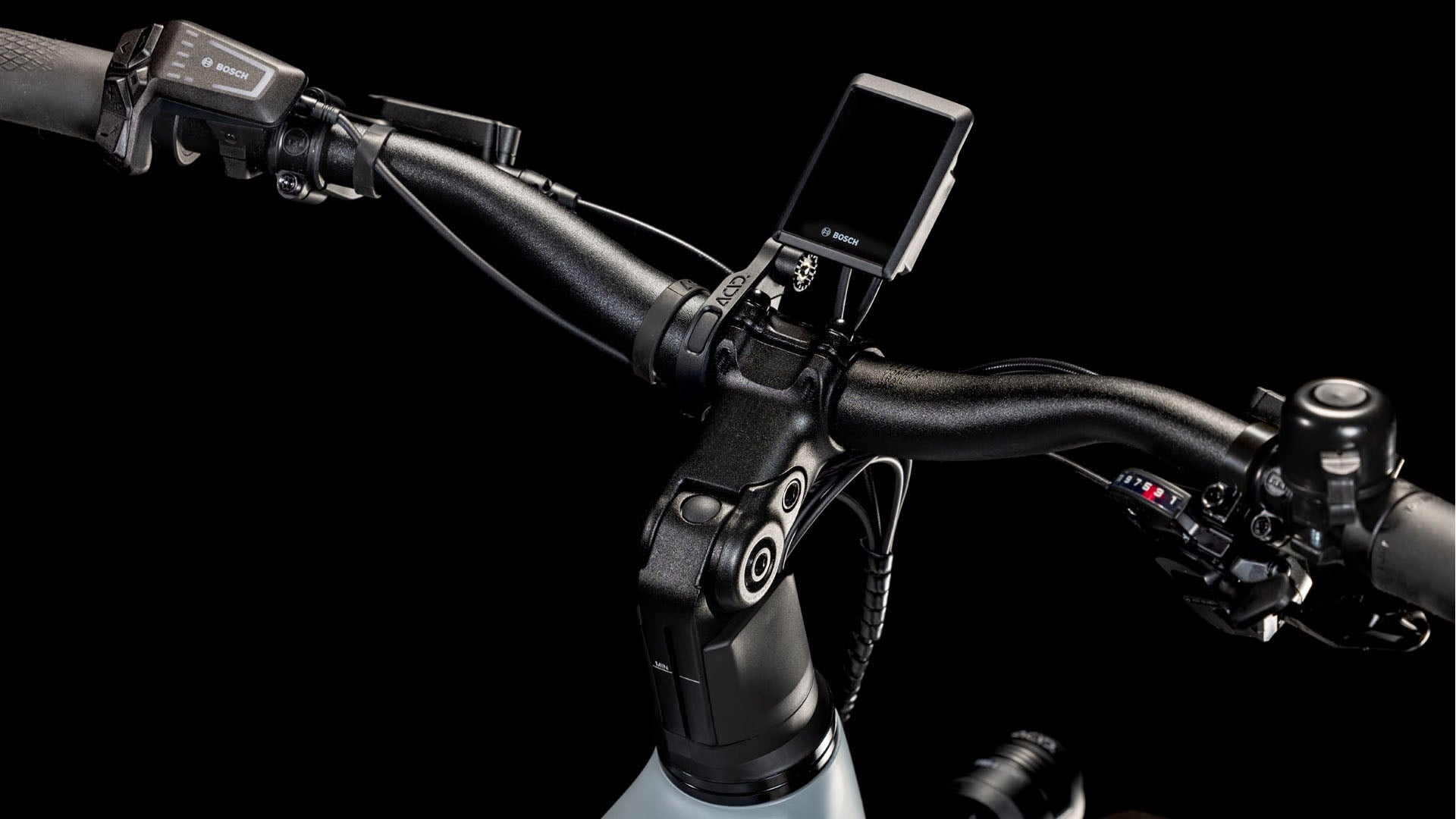 Nahaufnahme des CUBE Kathmandu Hybrid EX 800 haze´n´black Trapeze 2025-Lenkers mit Bosch-Display, Magura MT C ABS-Bedienelementen (links) und Gangschaltung (rechts) vor schwarzem Hintergrund.