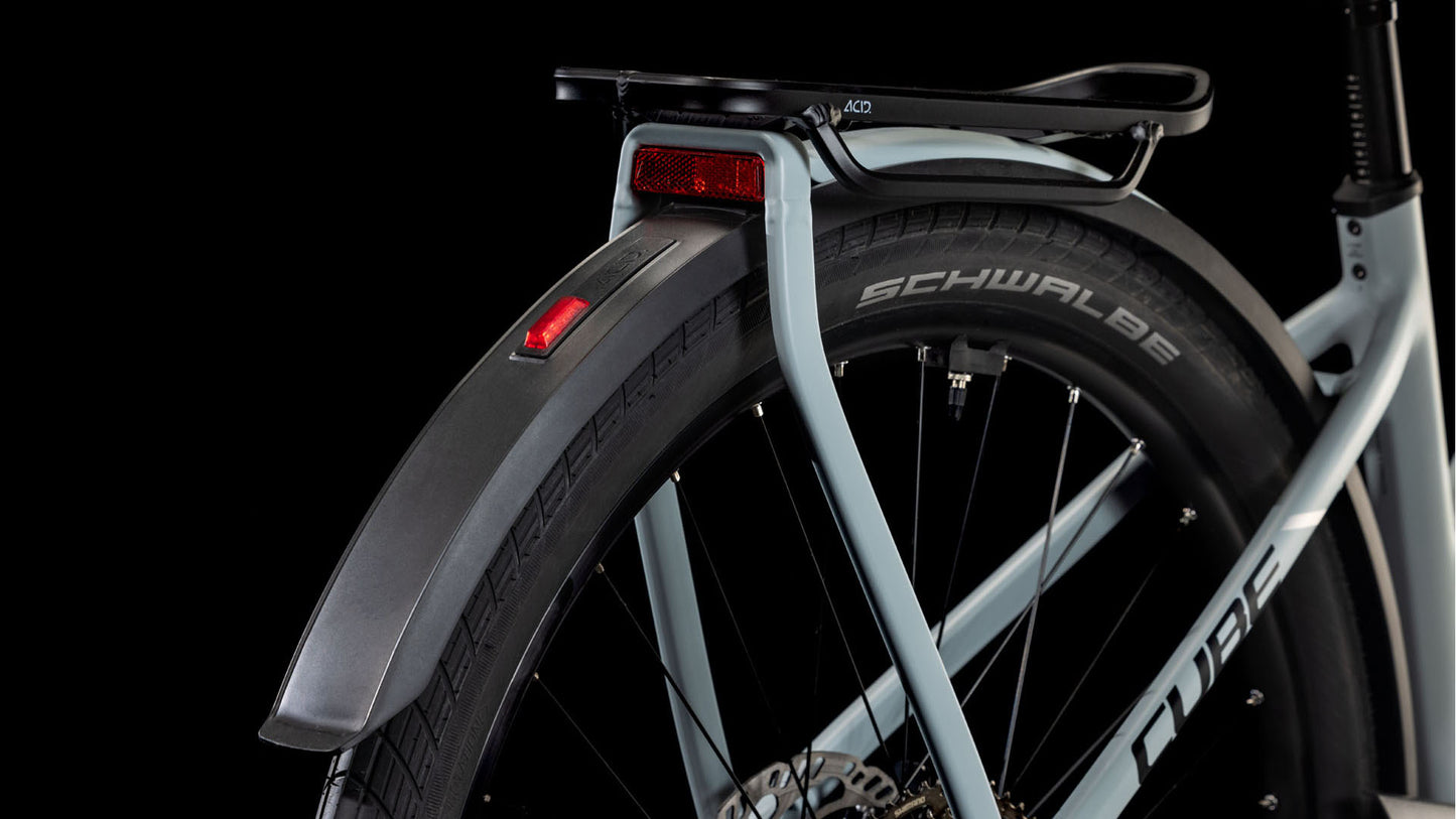 Nahaufnahme des Hinterrads und des Schutzblechs eines hellen CUBE Kathmandu Hybrid EX 800 haze´n´black Trapeze 2025 mit Gepäckträger, rotem Reflektor und sichtbaren Schwalbe-Reifen vor schwarzem Hintergrund.