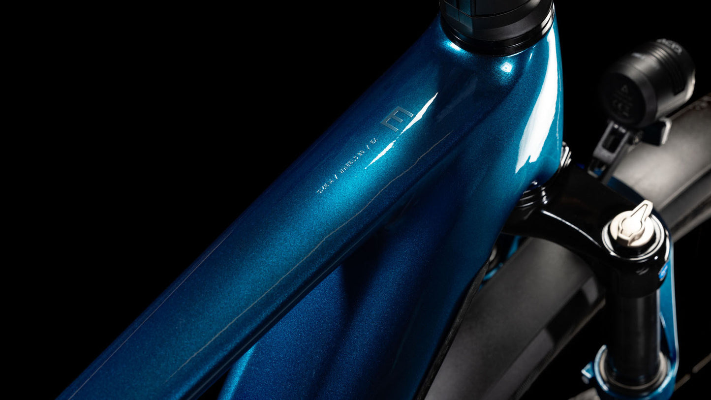 Nahaufnahme des CUBE Kathmandu Hybrid EX 800 electricblue´n´chrome 2025-Fahrradrahmens, der sein glänzendes Finish, seine schlanken Linien, einen Teil der Federgabel, den Reifen und die hydraulischen Scheibenbremsen vor einem schwarzen Hintergrund zeigt.