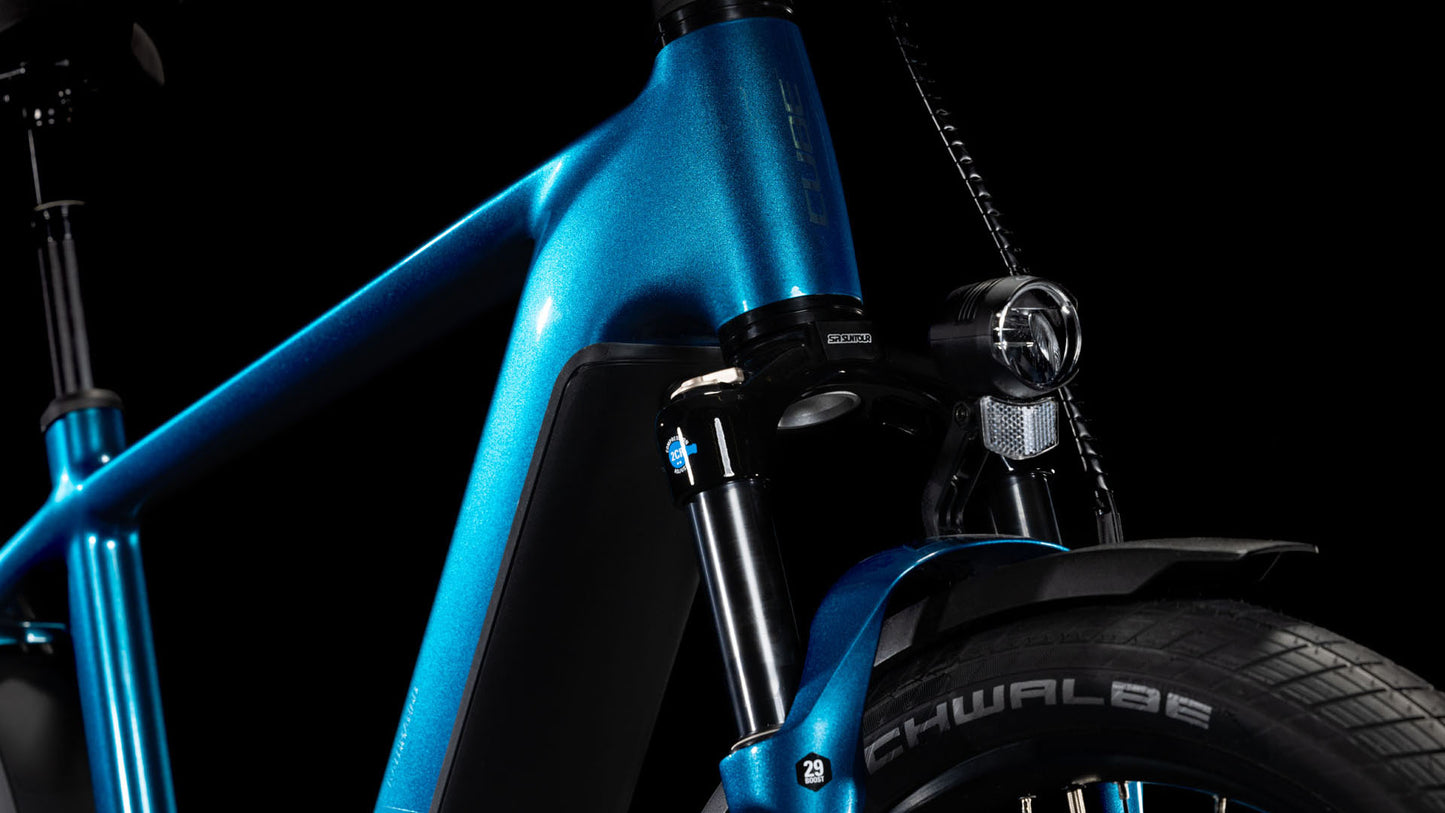 Nahaufnahme der Vorderseite des CUBE Kathmandu Hybrid EX 800 electricblue´n´chrome 2025. Zu sehen sind das Steuerrohr, die Vorderradgabel, der Bosch CX-Motor, der montierte Scheinwerfer, das Schwalbe-Reifenbranding und das Schutzblech vor einem schwarzen Hintergrund.