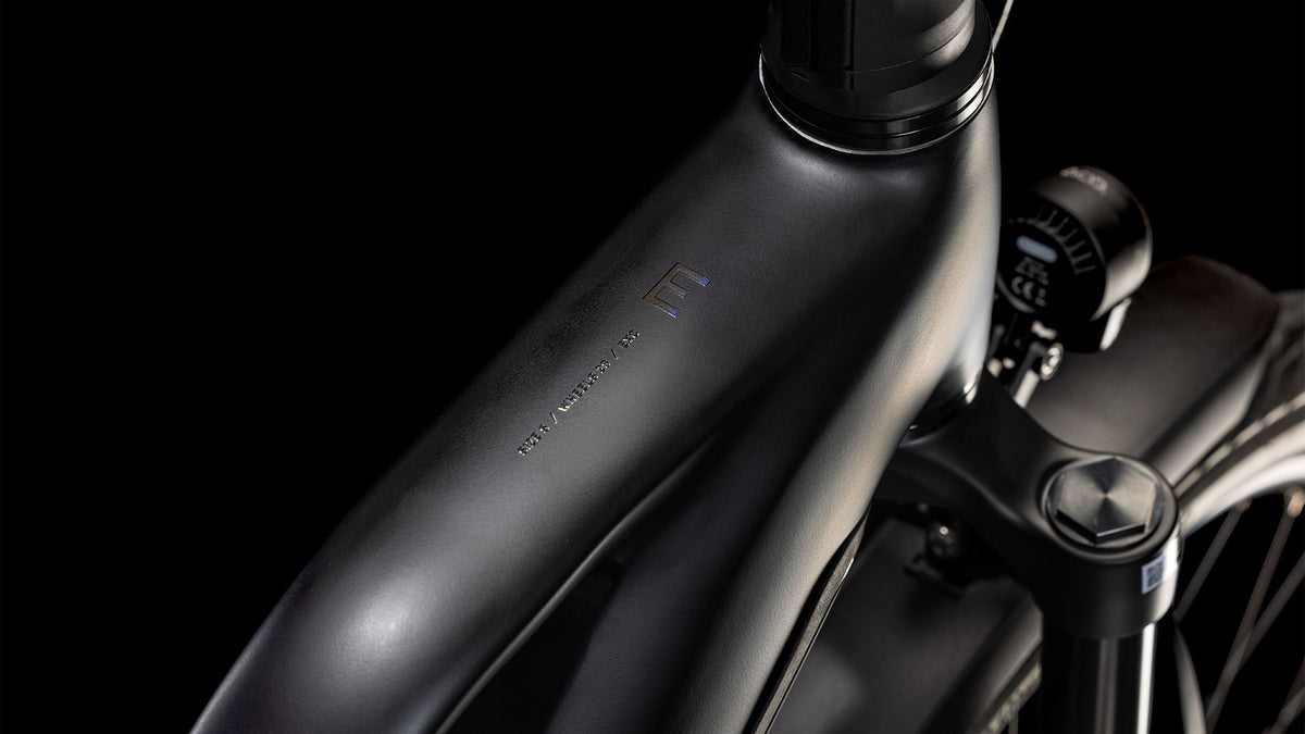 Der elegante CUBE Kathmandu Hybrid EXC 800 black'n'prism Trapeze 2025 Rahmen mit minimalistischem Branding, Bosch CX Motor, Shimano XT Schaltung und einer Digitalanzeige am Lenker vor schwarzem Hintergrund.