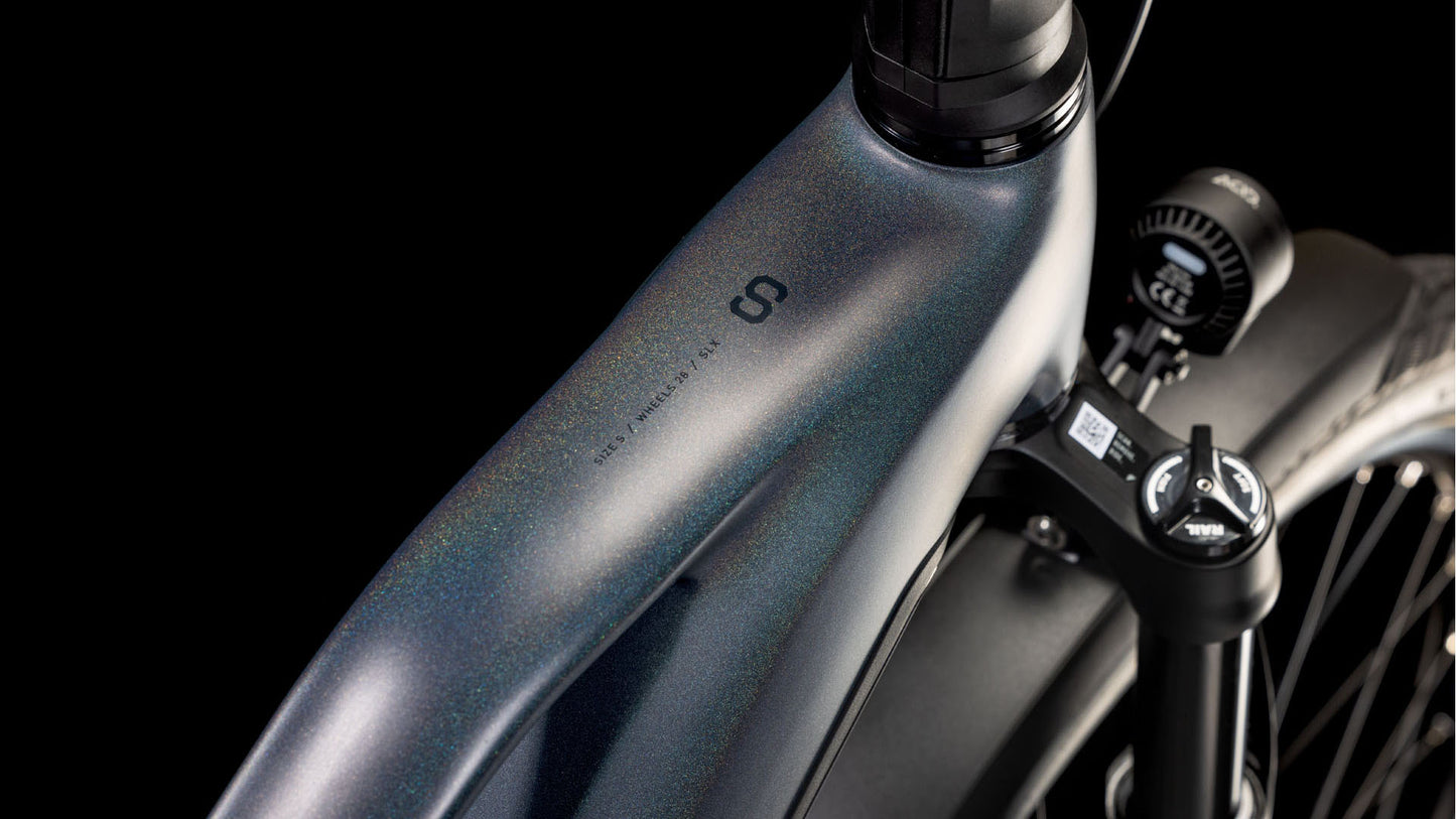 Nahaufnahme des Metallrahmens und der Vorderradaufhängung des CUBE Kathmandu Hybrid Comfort SLX 800 nightsky´n´ink Trapeze 2025. Zu sehen sind schillernde Lackierung, Bosch CX-Motor, Scheinwerfer und die detaillierte Konstruktion von CUBE vor einem schwarzen Hintergrund.