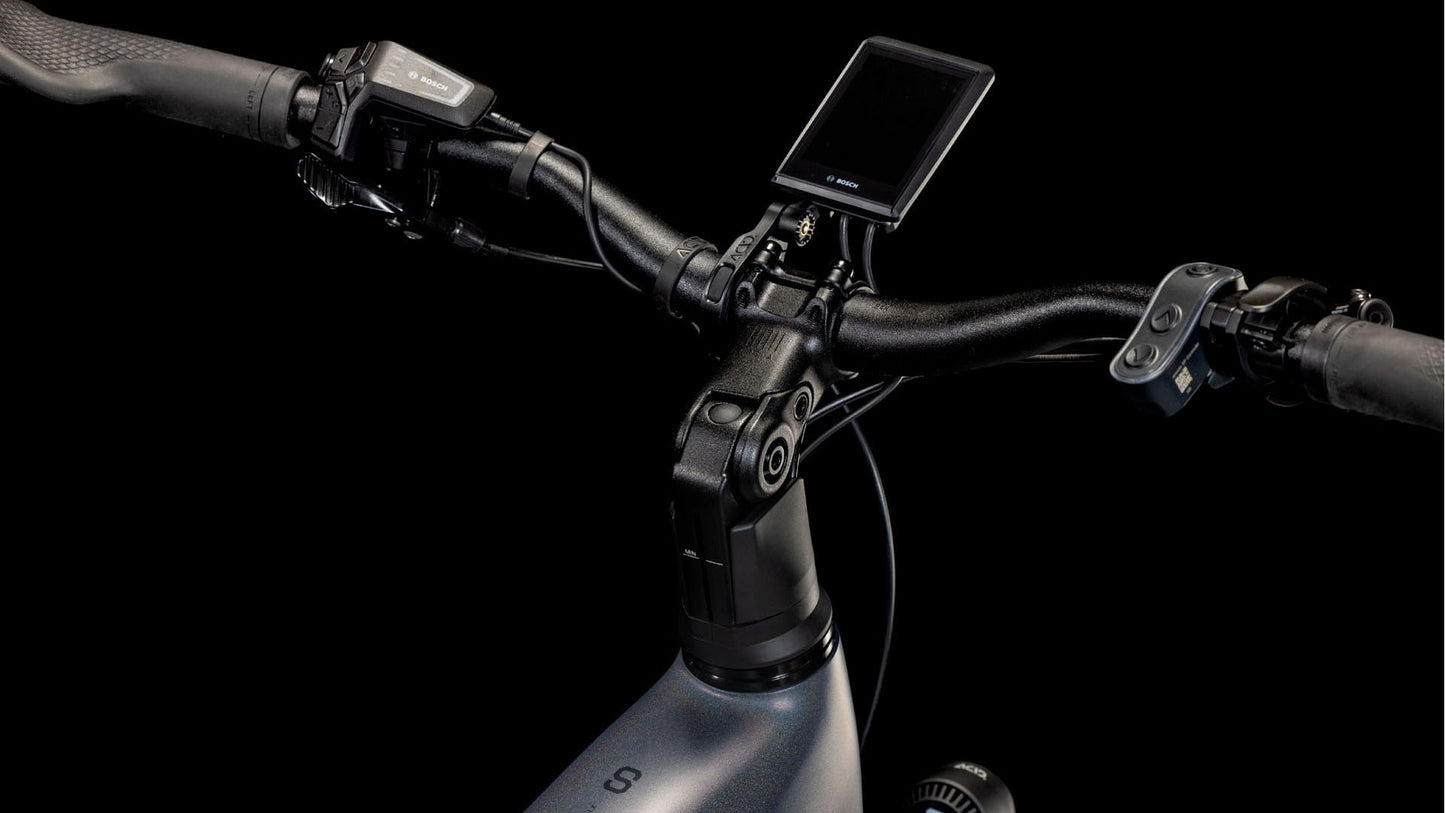 Nahaufnahme des Lenkers des CUBE Kathmandu Hybrid Comfort SLX 800 nightsky´n´ink Trapeze 2025. Zu sehen sind eine digitale Anzeige, Steuertasten und Bosch CX-Motorsteuerung vor einem schwarzen Hintergrund.