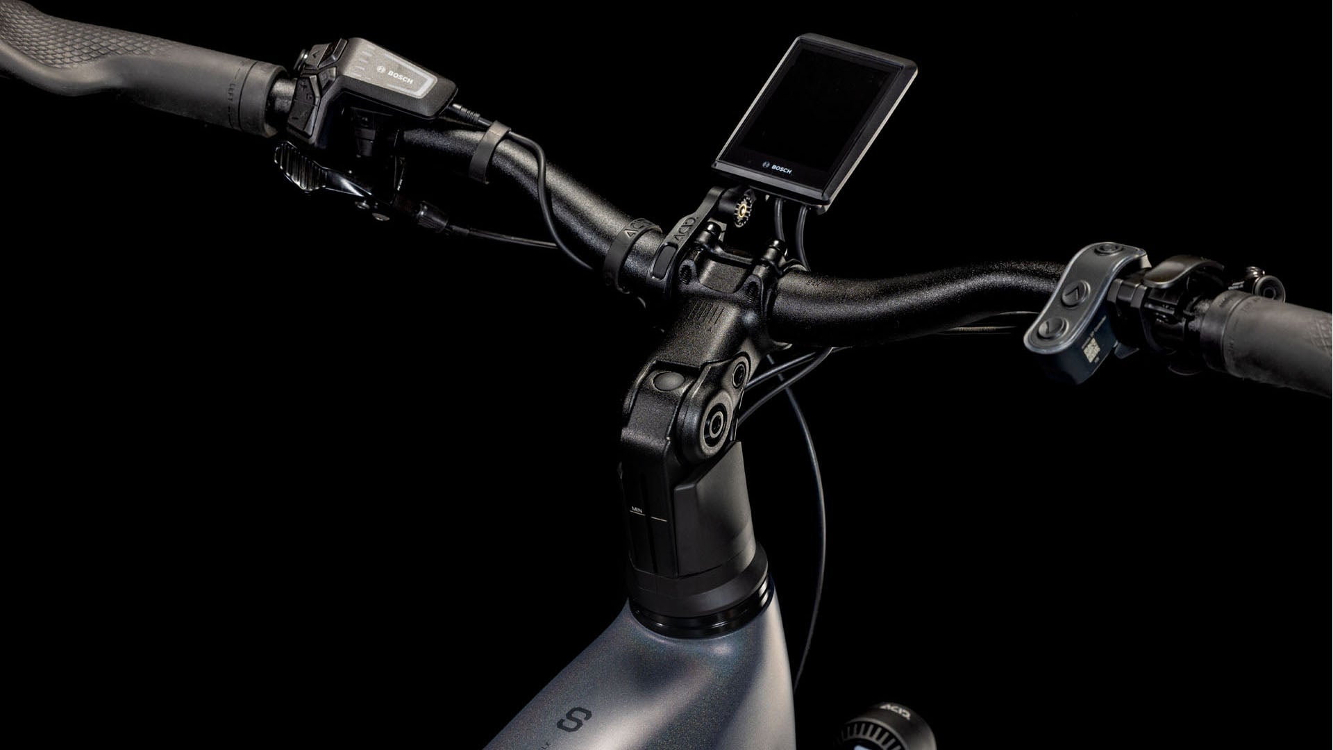 Nahaufnahme des Lenkers des CUBE Kathmandu Hybrid Comfort SLX 800 nightsky´n´ink Trapeze 2025. Zu sehen sind eine digitale Anzeige, Steuertasten und Bosch CX-Motorsteuerung vor einem schwarzen Hintergrund.