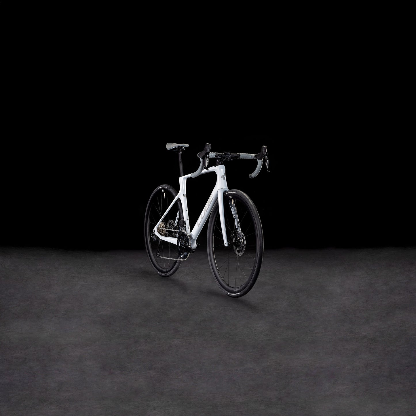 Das CUBE Agree C:62 ONE foggrey'n'grey 2025 Rennrad hebt sich mit seinem modernen Rahmen, der Shimano 105 Di2 Gruppe, dem tiefen Lenker und der schnittigen Bereifung von einem dunklen Hintergrund ab.