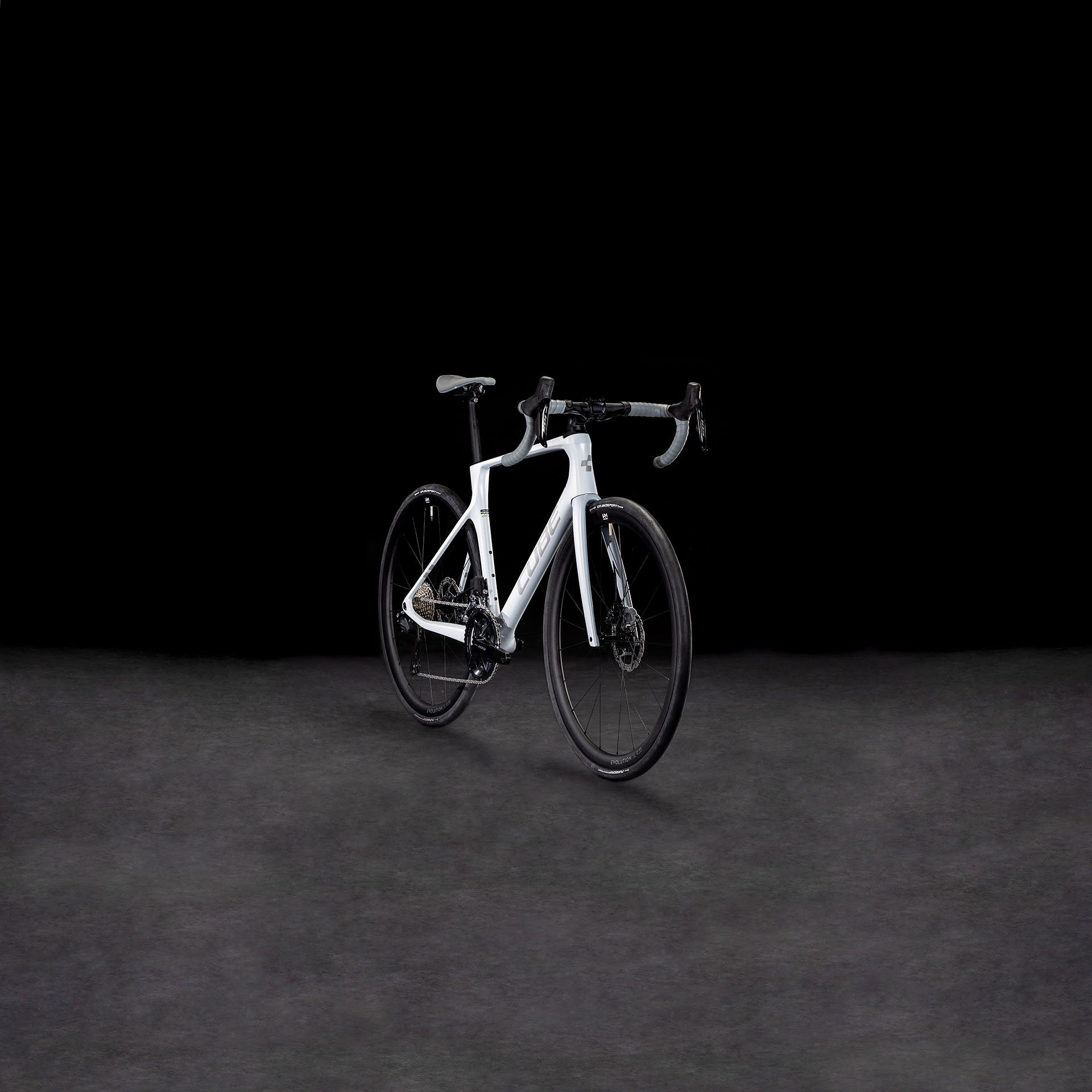 Das CUBE Agree C:62 ONE foggrey'n'grey 2025 Rennrad hebt sich mit seinem modernen Rahmen, der Shimano 105 Di2 Gruppe, dem tiefen Lenker und der schnittigen Bereifung von einem dunklen Hintergrund ab.