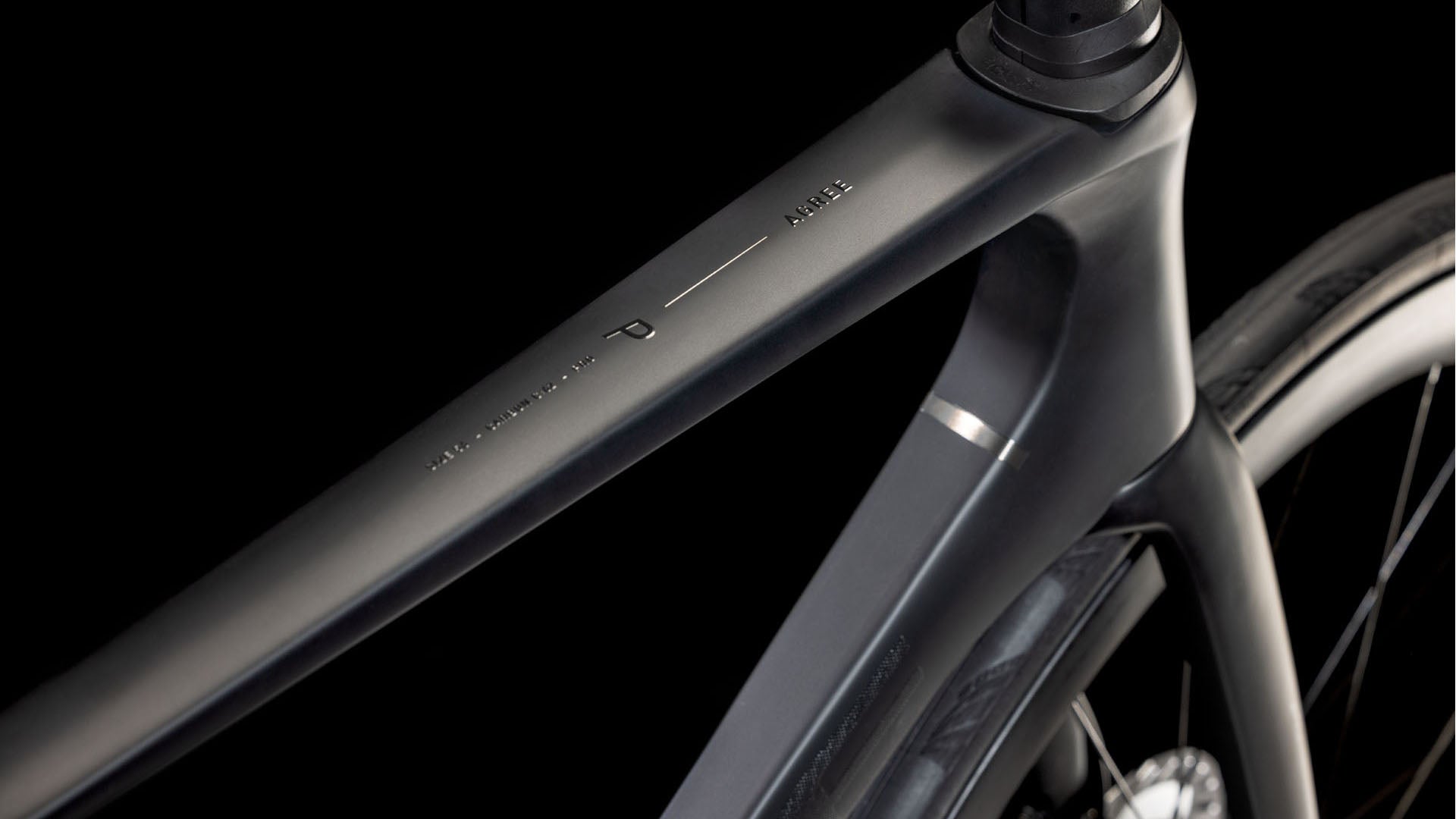 Nahaufnahme des mattschwarzen Carbon-Oberrohrs und Steuerrohrs des CUBE Agree C:62 Pro blackline 2025 mit minimalistischem Design und dezenter Shimano Ultegra Di2 Beschriftung vor einem dunklen Hintergrund.