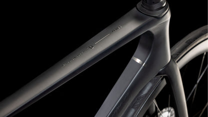 Nahaufnahme des mattschwarzen Carbon-Oberrohrs und Steuerrohrs des CUBE Agree C:62 Pro blackline 2025 mit minimalistischem Design und dezenter Shimano Ultegra Di2 Beschriftung vor einem dunklen Hintergrund.