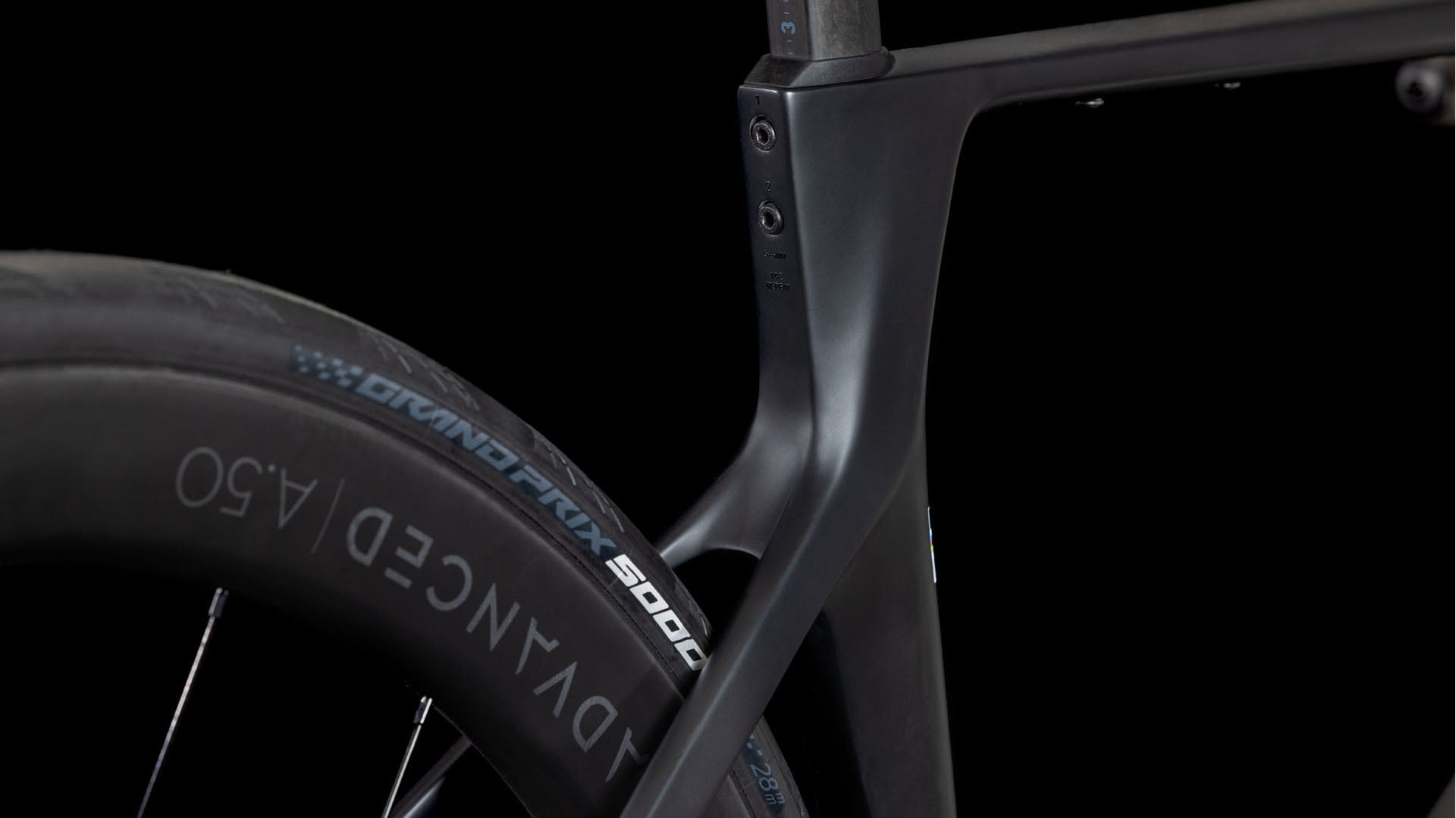 Nahaufnahme des Cube Agree C:62 Pro blackline 2025 von CUBE, die den mattschwarzen Carbonrahmen und das Hinterrad mit dem Schriftzug ADVANCED 4.50" auf dem Reifen hervorhebt - ein aerodynamisches Design, das sich ideal für Straßenrennen eignet, vor schwarzem Hintergrund.