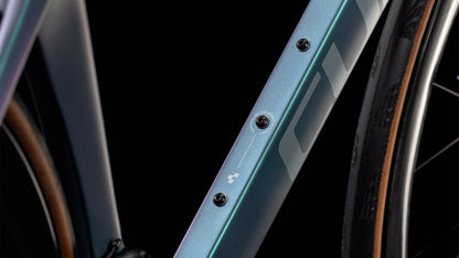 Nahaufnahme des CUBE Agree C:62 Pro polarlight'n'aquagreen 2025-Rahmens mit metallisch blauem Carbon, drei Befestigungsschrauben, einem kleinen weißen Logo und einem Teil eines Reifens auf der rechten Seite vor einem schwarzen Hintergrund.