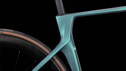 Nahaufnahme des CUBE Agree C:62 Pro polarlight'n'aquagreen 2025 Rahmens und des Hinterrads, das ein glattes, metallisches Teal-Finish aufweist. Die hellbraune Seitenwand des Reifens und das detaillierte Profil heben die Handwerkskunst von CUBE vor einem schwarzen Hintergrund hervor.