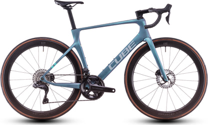 Das CUBE Agree C:62 Pro polarlight'n'aquagreen 2025 ist ein schlankes, modernes Rennrad mit tiefem Lenker, Scheibenbremsen, Carbon-Laufrädern mit tiefem Querschnitt, Shimano Ultegra Di2 und einem auffälligen CUBE-Branding auf dem Rahmen.