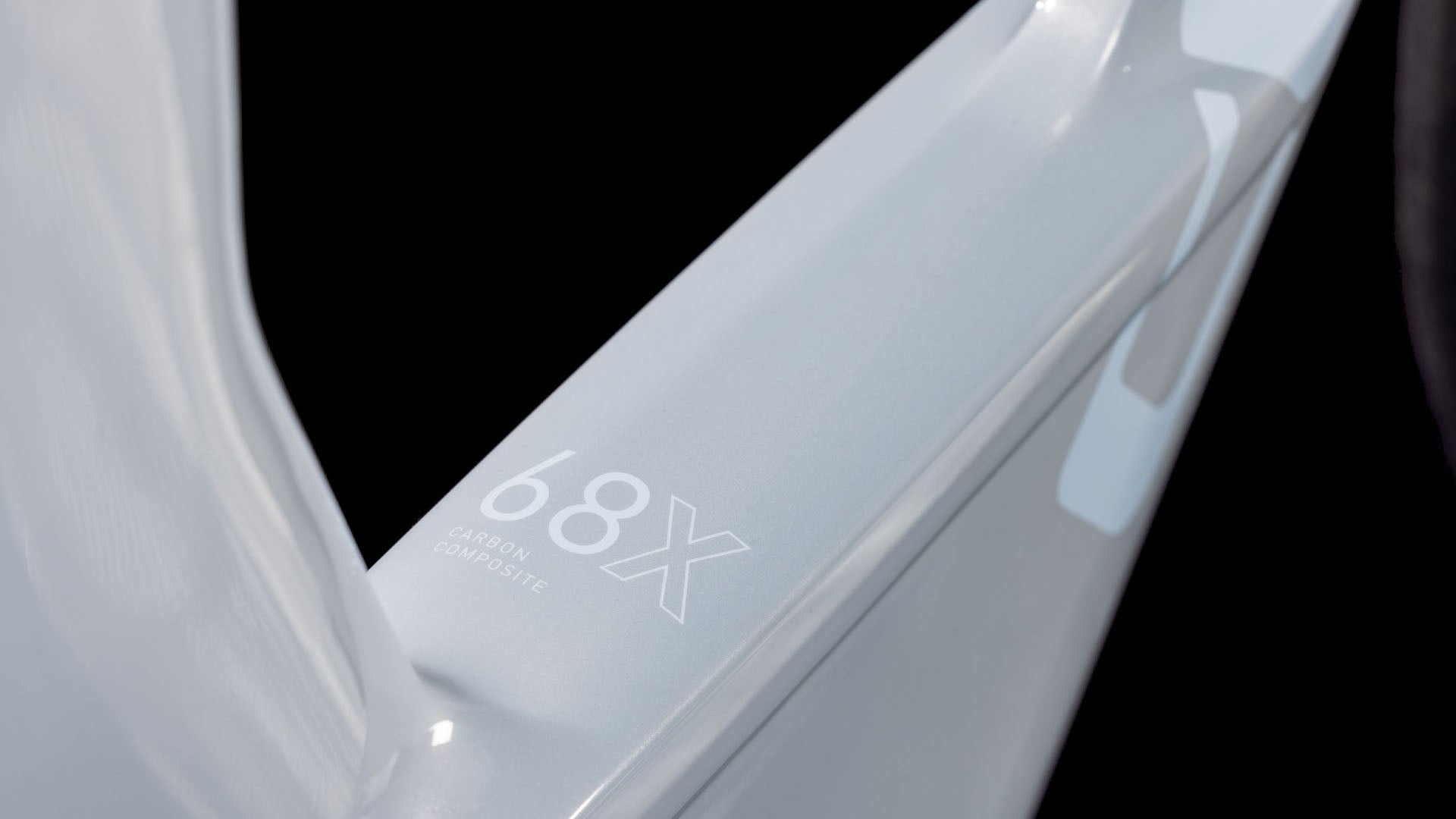 Nahaufnahme einer hellgrauen, glänzenden Oberfläche mit der Aufschrift "68X Carbon Composite" in Weiß auf Schwarz - Teil des CUBE Aerium C:68X Race foggrey'n'white 2026 Triathlonrads.