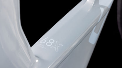 Nahaufnahme einer hellgrauen, glänzenden Oberfläche mit der Aufschrift "68X Carbon Composite" in Weiß auf Schwarz - Teil des CUBE Aerium C:68X Race foggrey'n'white 2026 Triathlonrads.