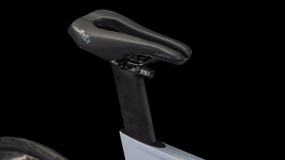Nahaufnahme eines schwarzen aerodynamischen Sattels auf dem CUBE Aerium C:68X Race foggrey'n'white 2026 Triathlonrad mit Kohlefaser-Sattelstütze und Shimano Ultegra Di2, vor schwarzem Hintergrund. Das Hinterrad ist am linken Rand teilweise sichtbar.