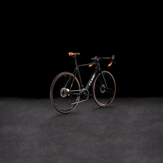 Das CUBE Cross Race C:62 Pro carbon'n'orange 2025 Rennrad mit Carbonrahmen und auffälligen orangefarbenen Akzenten wird vor einem dunklen Hintergrund präsentiert, um sein modernes, aerodynamisches Design zu unterstreichen.