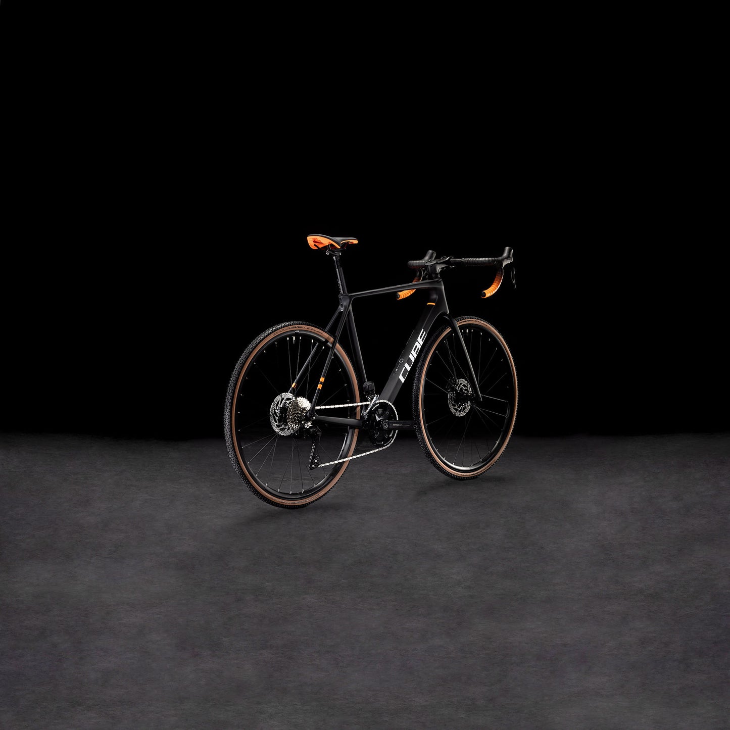 Das CUBE Cross Race C:62 Pro carbon'n'orange 2025 Rennrad mit Carbonrahmen und auffälligen orangefarbenen Akzenten wird vor einem dunklen Hintergrund präsentiert, um sein modernes, aerodynamisches Design zu unterstreichen.