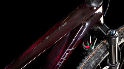 Nahaufnahme des Oberrohrs und der Vorderrad-Federgabel eines CUBE Stereo ONE44 C:68X SLX 29 liquidviolet'n'black 2025 Mountainbikes. Zu sehen sind das STEREO-Label, das sichtbare Reifenprofil und Rahmendetails vor einem schwarzen Hintergrund.