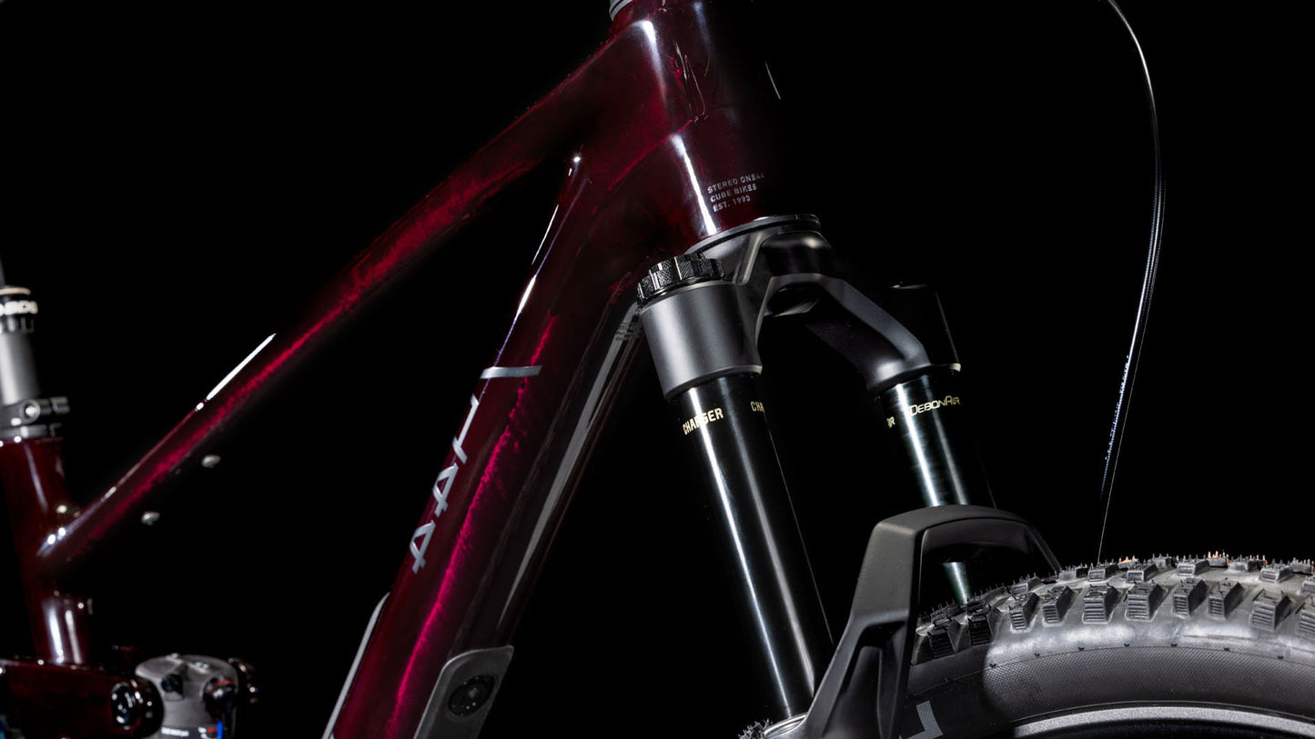 Nahaufnahme eines CUBE Stereo ONE44 C:68X SLX 29 liquidviolet'n'black 2025 Carbon-Rahmens. Hervorzuheben sind die Federgabel und der Noppenreifen mit SRAM GX Eagle-Getriebe vor einem schwarzen Hintergrund.