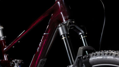 Nahaufnahme eines CUBE Stereo ONE44 C:68X SLX 29 liquidviolet'n'black 2025 Carbon-Rahmens. Hervorzuheben sind die Federgabel und der Noppenreifen mit SRAM GX Eagle-Getriebe vor einem schwarzen Hintergrund.