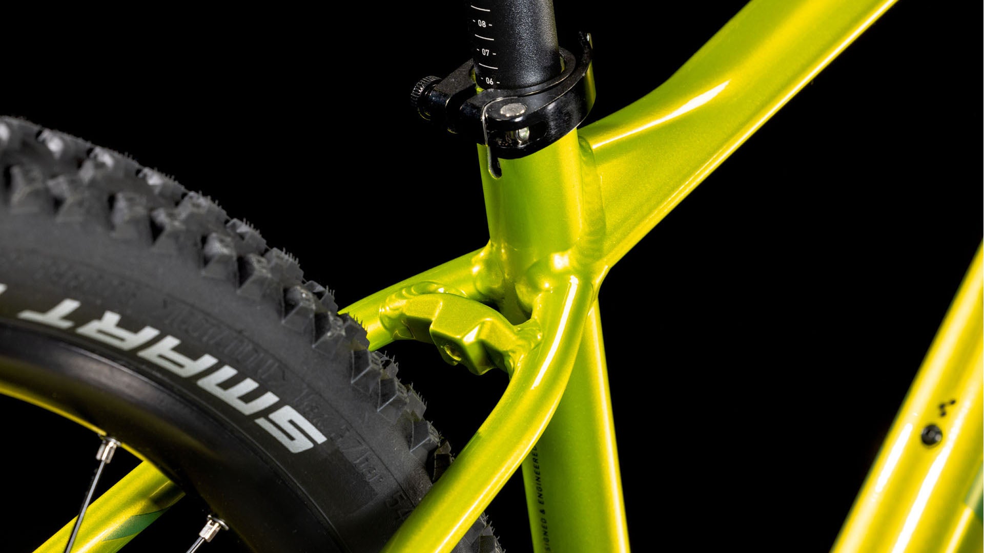 Nahaufnahme des CUBE Aim SLX Flashlime´n´Juniper 2025 Fahrradrahmens mit hervorgehobener Sattelstütze und oberem Hinterrad mit SMART-Reifenlogo und 11-facher Cues-Schaltung vor schwarzem Hintergrund.