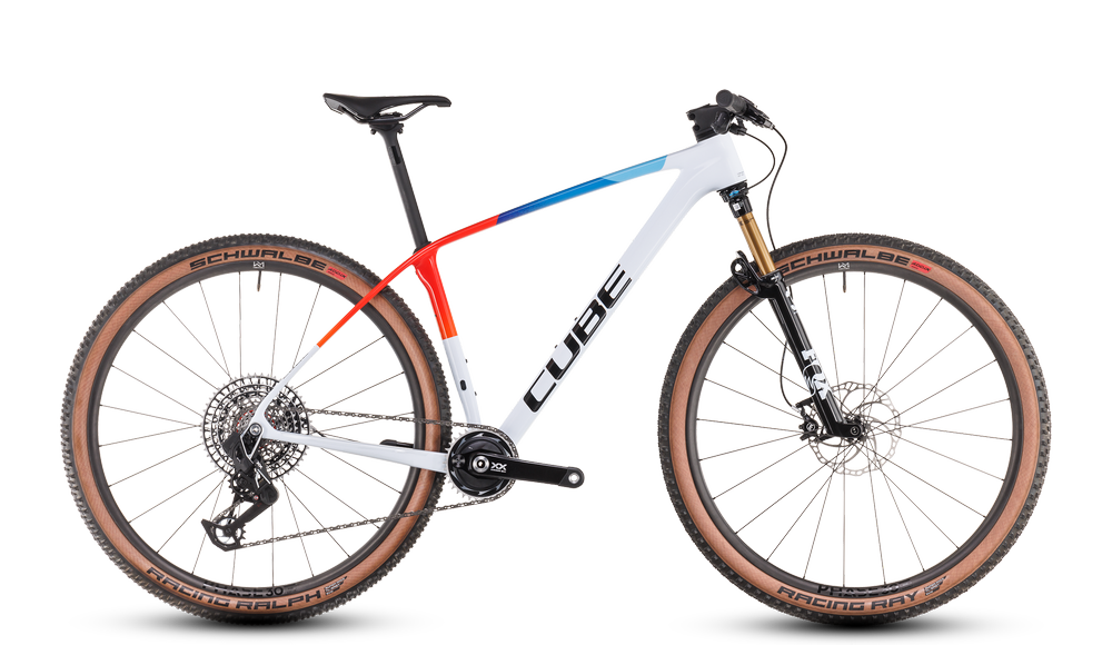 Das CUBE Phenix C:68X SLT teamline 2025 ist ein modernes Mountainbike mit weißem Rahmen, schwarzen und blauen Akzenten, braunen Schwalbe-Reifen, Fox Float 32 Factory SC Vorderradfederung, flachem Lenker und auffälligem CUBE Branding.