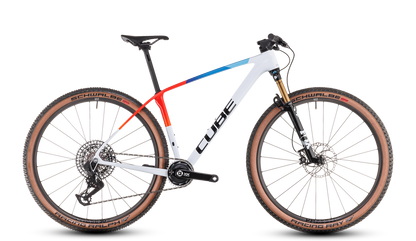 Das CUBE Phenix C:68X SLT teamline 2025 ist ein modernes Mountainbike mit weißem Rahmen, schwarzen und blauen Akzenten, braunen Schwalbe-Reifen, Fox Float 32 Factory SC Vorderradfederung, flachem Lenker und auffälligem CUBE Branding.