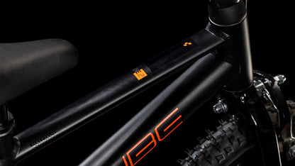 Nahaufnahme eines CUBE Numove 120 RT black'n'orange 2025 Rahmens mit orangem Schriftzug, der den Sitz, das Oberrohr und einen Teil des Hinterrads vor einem schwarzen Hintergrund zeigt.