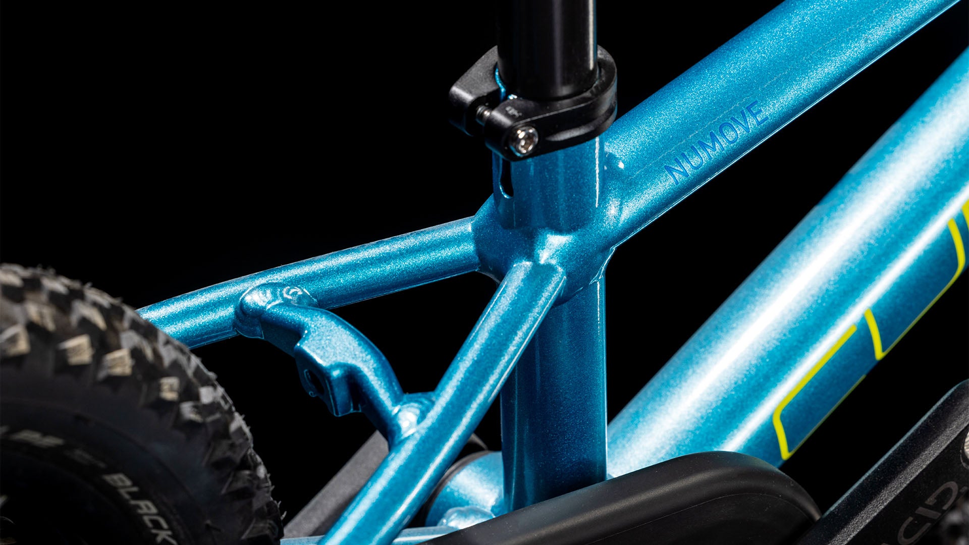 Nahaufnahme des CUBE Cube Numove 120 RT blue'n'lime 2025, die den blauen Aluminiumrahmen, die Sattelstütze, den Hinterreifen und einen Teil des Kettenschutzes hervorhebt. Das metallische Finish und die sauberen Schweißnähte sind sichtbar, mit einer Felgenbremse vor schwarzem Hintergrund.