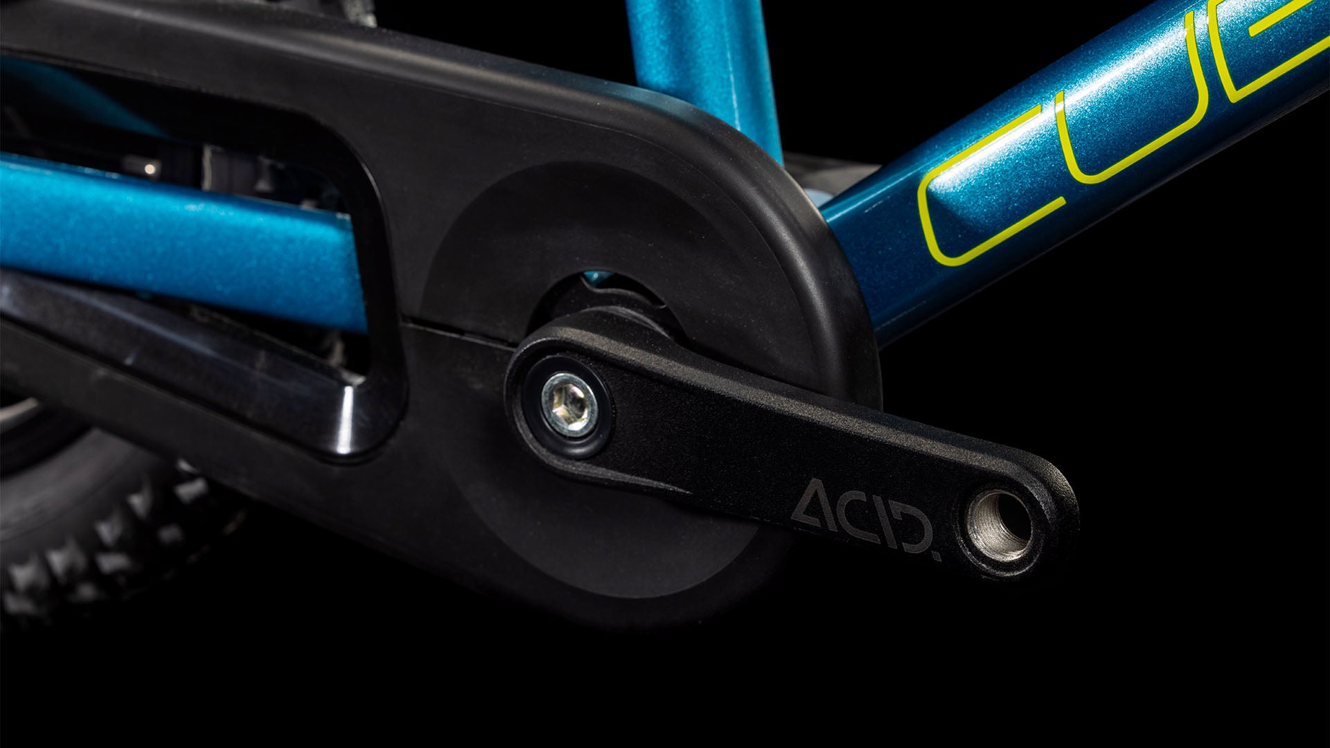 Nahaufnahme des CUBE Numove 120 RT blue'n'lime 2025 Aluminiumrahmens mit Kurbelarm, Pedalachse und Kettenschutz, mit ACID auf dem Kurbelarm und teilweisem CUBE Branding auf dem Rahmen.