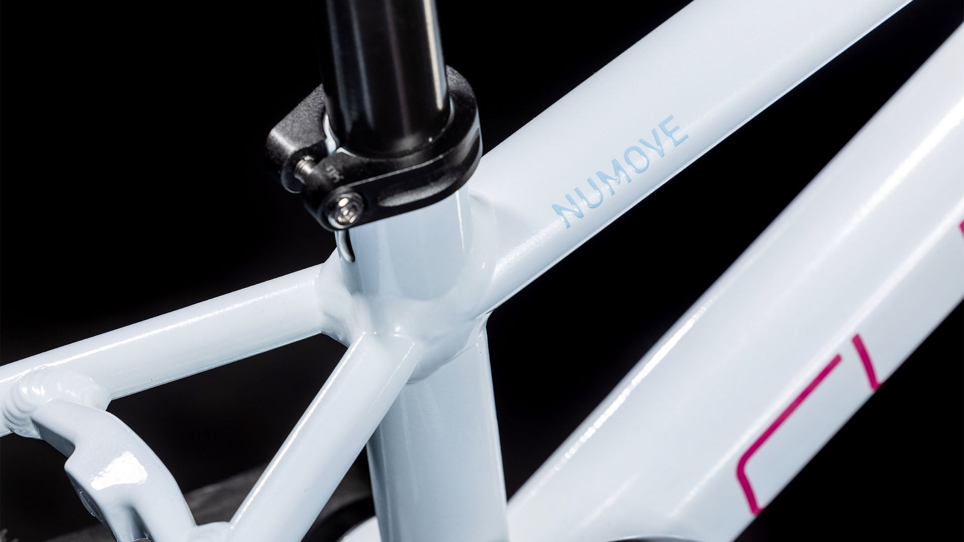 Nahaufnahme des Cube Numove 120 RT flashwhite'n'pink 2025 von CUBE, die das Sattelrohr, die Sattelstützenklemme und das NUMOVE-Branding auf dem hellblauen Aluminiumrahmen vor schwarzem Hintergrund zeigt.