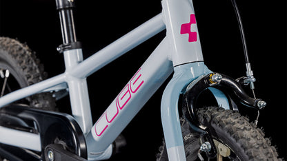 Nahaufnahme eines CUBE Numove 120 RT flashwhite'n'pink 2025, die den Aluminiumrahmen, die Federgabel, die Vorderbremse, das Reifenprofil und einen Teil des Lenkers vor einem schwarzen Hintergrund zeigt.