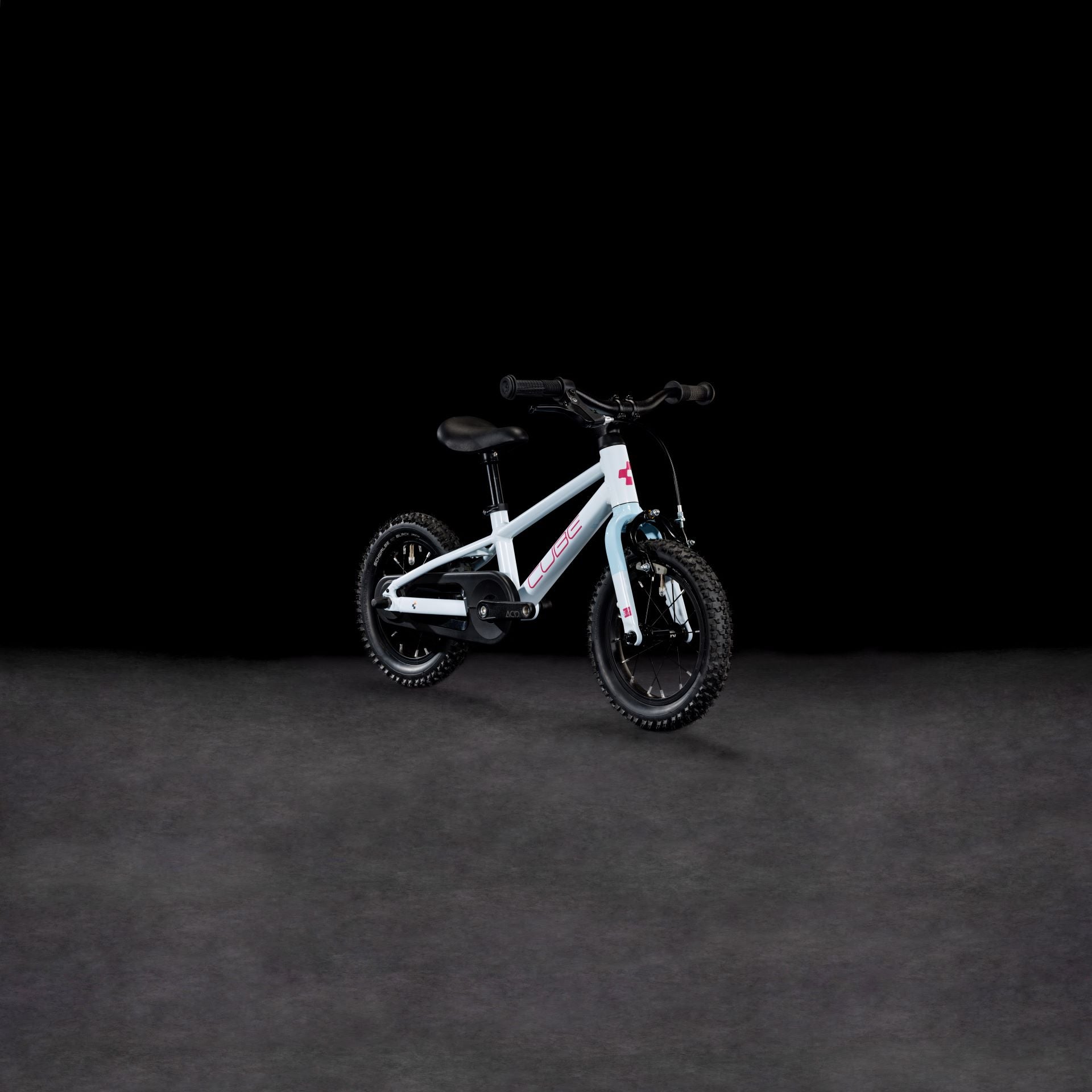 Ein CUBE Numove 120 RT flashwhite'n'pink 2025 Kinderfahrrad mit Stützrädern und einem stabilen Aluminiumrahmen wird vor einem schlichten schwarzen Hintergrund präsentiert.