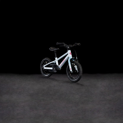 Ein CUBE Numove 120 RT flashwhite'n'pink 2025 Kinderfahrrad mit Stützrädern und einem stabilen Aluminiumrahmen wird vor einem schlichten schwarzen Hintergrund präsentiert.