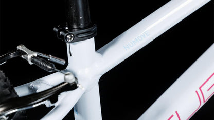 Nahaufnahme des CUBE Numove 140 flashwhite'n'pink 2025 Rahmens mit kindgerechten V-Brakes, die das Sitzrohr, die Hinterradbremse und NUMOVE auf der Rahmenbauweise von CUBE vor einem schwarzen Hintergrund zeigt.