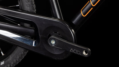 Nahaufnahme eines schwarzen ACID-Kurbelarms, eines Kettenblatts und eines Schwalbe-Reifens am Hinterrad vor einem schwarzen Hintergrund. Der Rahmen des CUBE Numove 180 black'n'orange 2025 All-Terrain-Bikes sticht mit seinen kräftigen orangen Akzenten hervor.