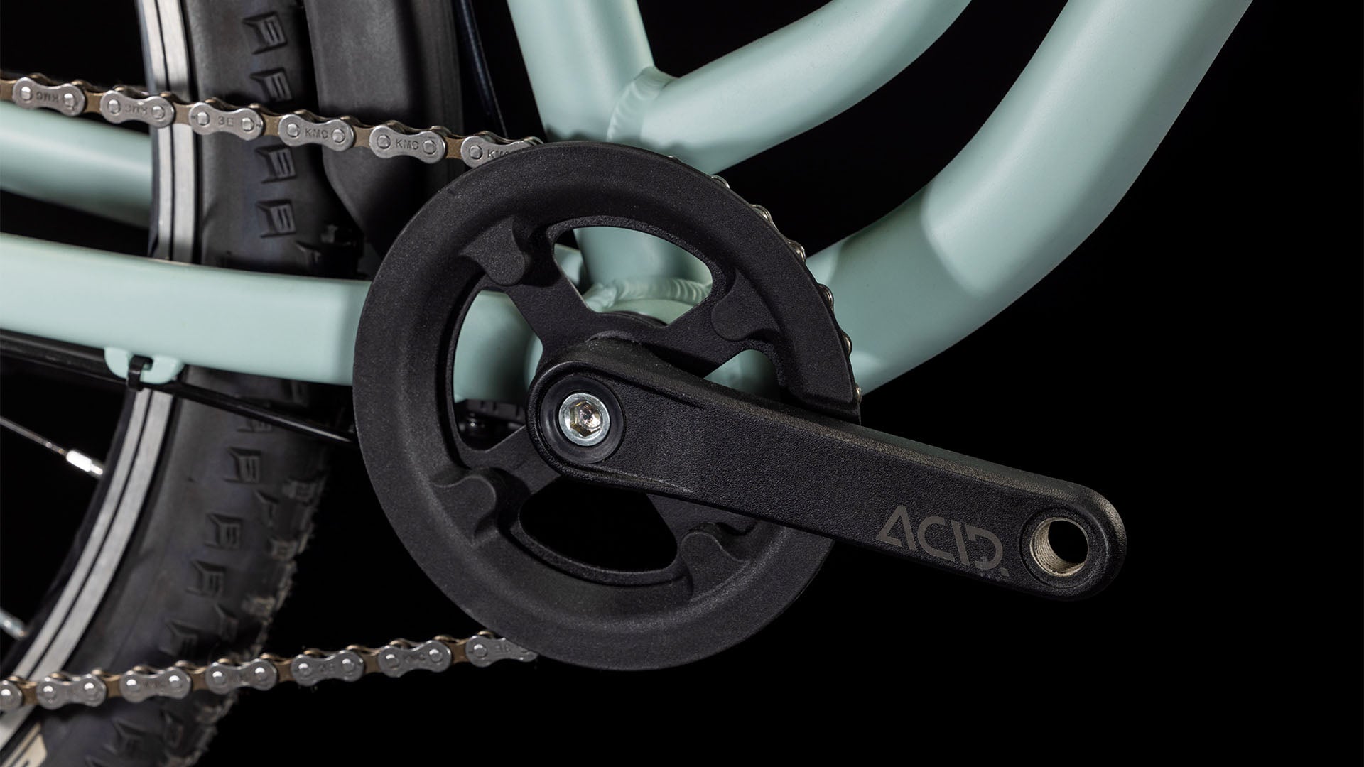 Nahaufnahme der CUBE Ella 240 aloegreen'n'white 2025 Fahrradkurbelgarnitur mit schwarzem ACID-Schriftzug auf Kurbelarm, Kettenblatt, Teil des Shimano 3x8-Antriebssystems, Rahmenteil und Kette vor schwarzem Hintergrund. Marke: CUBE.