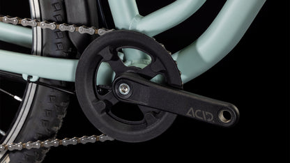 Nahaufnahme der CUBE Ella 240 aloegreen'n'white 2025 Fahrradkurbelgarnitur mit schwarzem ACID-Schriftzug auf Kurbelarm, Kettenblatt, Teil des Shimano 3x8-Antriebssystems, Rahmenteil und Kette vor schwarzem Hintergrund. Marke: CUBE.