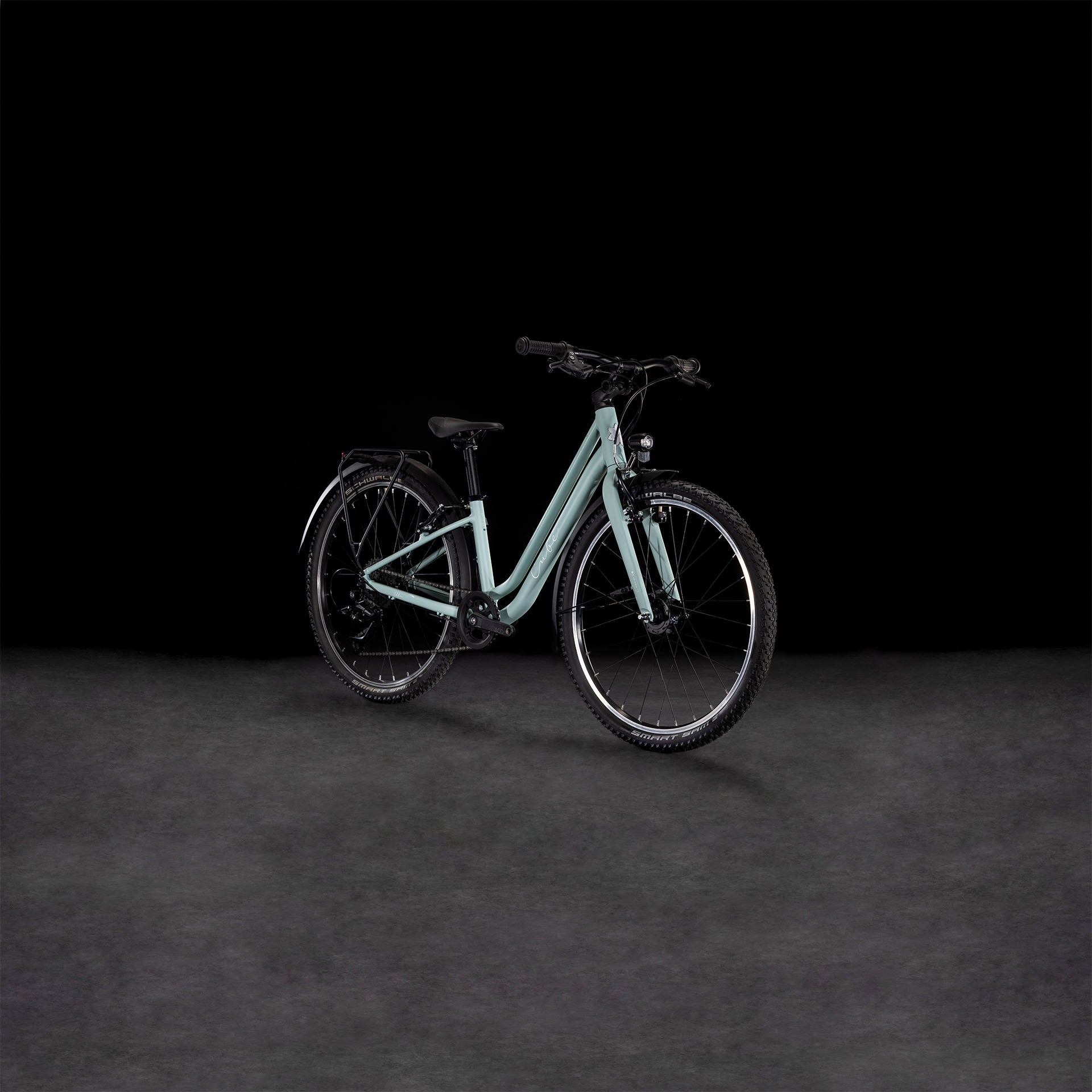 Das CUBE Ella 240 aloegreen'n'white 2025, ein Tiefeinsteigerrahmenrad von CUBE mit schwarzer Bereifung, Shimano 3x8-Schaltung und einem Gepäckträger wird auf einer grauen Fläche vor schwarzem Hintergrund gezeigt.