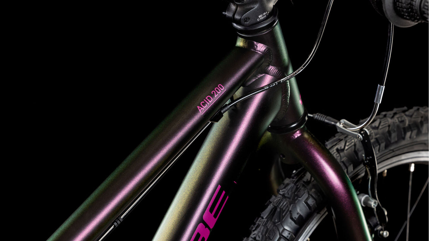 Nahaufnahme des CUBE Acid 200 molotov'n'pink 2025 von CUBE, die den robusten 6061 Aluminiumrahmen mit metallisch schillerndem Finish zeigt. Die Details des Rahmens, des Lenkers und des Vorderreifens heben sich von einem schwarzen Hintergrund ab.