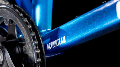 Nahaufnahme des blauen CUBE Acid 200 Disc Actionteam 2025-Rahmens mit dem Aufdruck „ACTIONTEAM“, neben der schwarz-silbernen Kurbelgarnitur und dem Kettenblatt vor schwarzem Hintergrund.